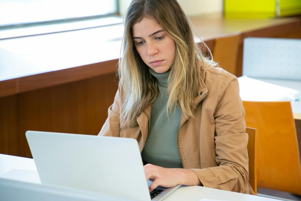 Young woman participating in a remote internship working on a computer in a cafe